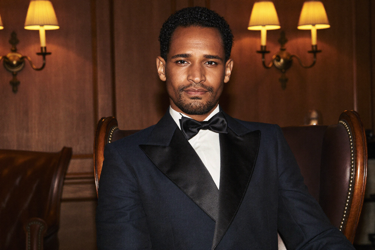 A man in a midnight-blue shawl-collar dinner jacket with silk facings in a wood-panelled club